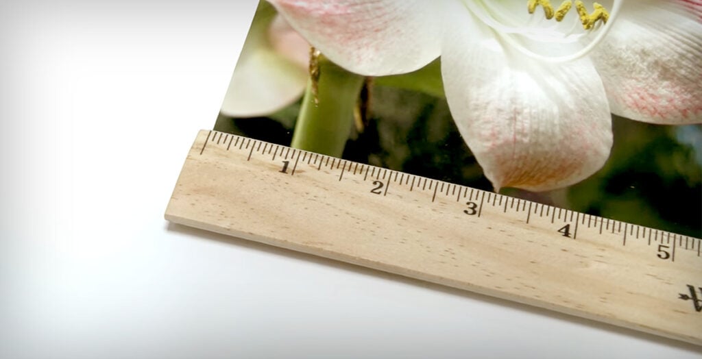 Using wooden ruler to measure photo. 